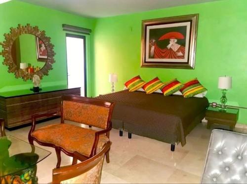 a green bedroom with a bed and a chair and a mirror at Hotel Arcadia in Chilpancingo de los Bravos