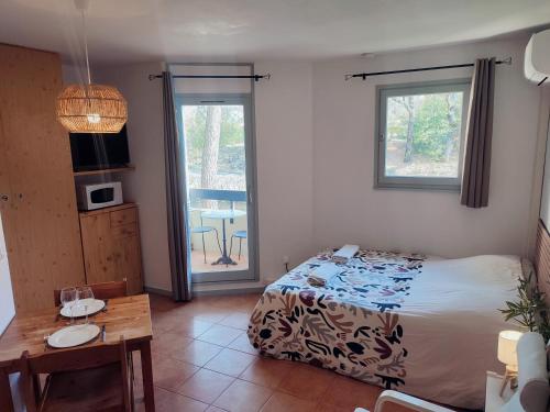 - une chambre avec un lit, une table et un balcon dans l'établissement Le studio des Garrigues - Climatisé, à Gréoux-les-Bains