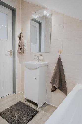 a white bathroom with a sink and a mirror at Kavárna a penzion Orava in Karviná