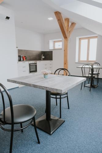 a table in a room with chairs and a kitchen at Kavárna a penzion Orava in Karviná