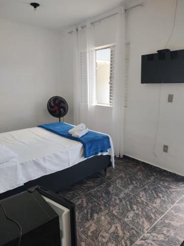 a bedroom with a bed and a tv and a window at Pousada Styllus Miguel Pereira in Miguel Pereira