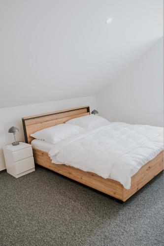 a bedroom with a wooden bed with white sheets at Kavárna a penzion Orava in Karviná