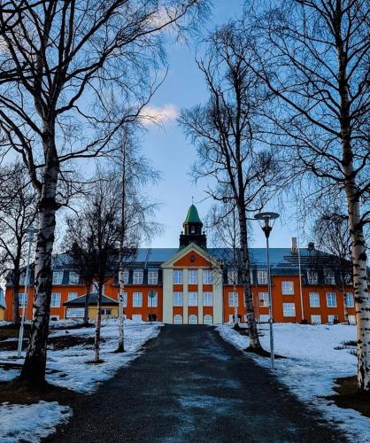 an orange building with a clock tower in the snow at City center Panorama in Tromsø