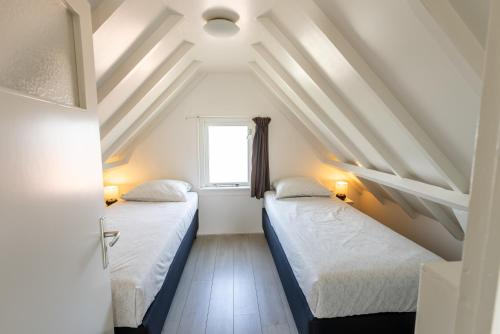 two beds in a room with a window at De Vrije wil in Buren