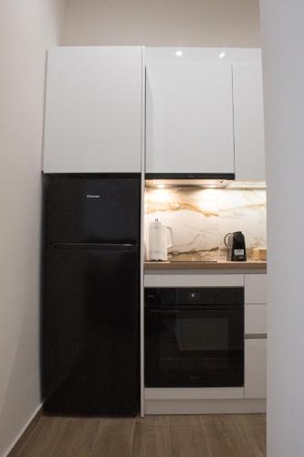 a kitchen with a black refrigerator and white cabinets at RAFINAS PARADISE VIEW!! Walking access to the Port!! Amazing Seaview!!! in Rafina