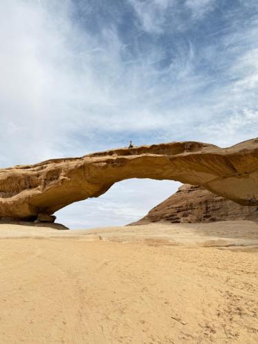 a person standing on top of an arch in the desert at Wadi Rum Sapphir camp in Disah