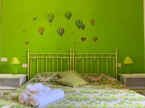 a green bedroom with a bed with towels and hot air balloons at Casa di Osio - Porta Romana in Siena