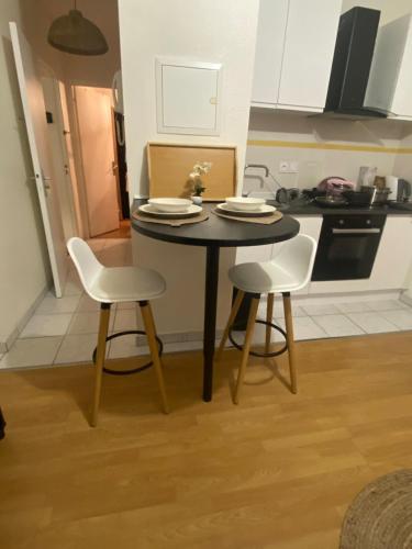 une petite table avec deux chaises et une cuisine dans l'établissement Le Petit Soleil, à Longwy