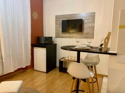 une cuisine avec une table avec des chaises et un micro-ondes dans l'établissement Le Petit Soleil, à Longwy