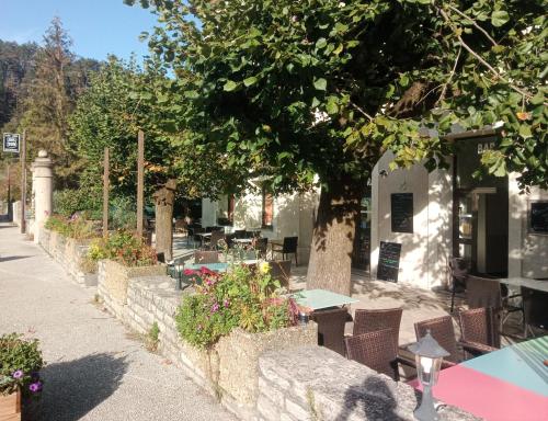a patio with tables and chairs under a tree at Route 999 in Alzon