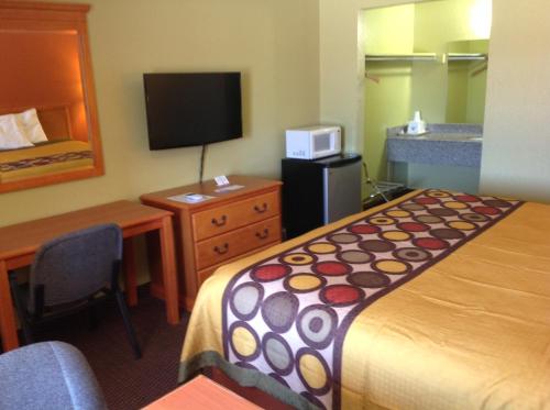 a hotel room with a bed and a desk and a television at Americas Best Value Inn Pryor in Pryor