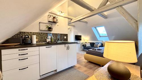 a kitchen with white cabinets and a living room at Ysenberc Apartments in Moritzburg