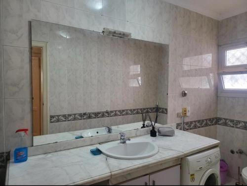 Un baño con lavabo y un espejo grande. en Aqua Maadi Degla Group, en El Cairo