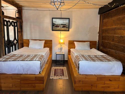 a bedroom with two beds and a table with a lamp at Hnameni Bovadzor Lodge in Maksim Gorʼkiy
