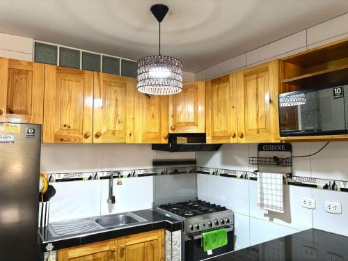 a kitchen with wooden cabinets and a stove top oven at Comfortable House in Punta Hermosa