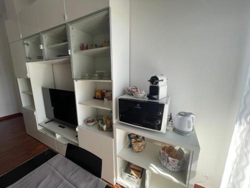 a kitchen with a microwave and a tv in a room at MMBook Casa Zucca Rho Fiera Milano in Rho