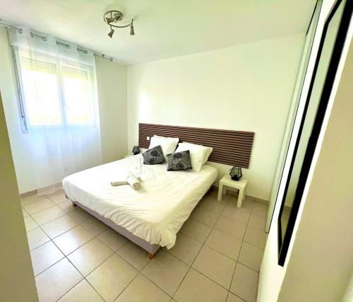 une chambre avec un lit blanc et une fenêtre dans l'établissement Marseille Superbe T2 Confort & Élégance Parking Privé & Piscine, à Marseille