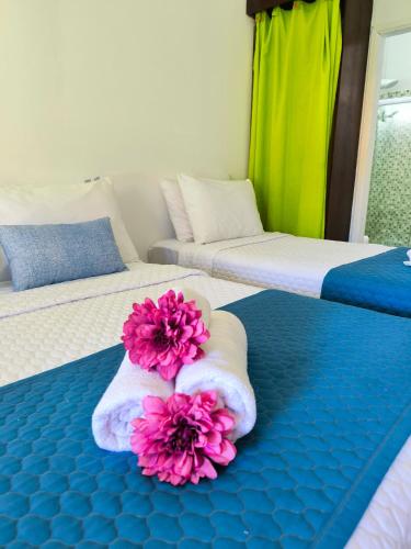 two beds with towels and pink flowers on them at Canto das Laranjeiras Vista Way in Guarujá