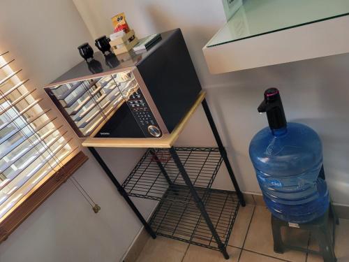 a small microwave on a stand with a large bottle of water at GR20acd Doris in Cuauhtémoc