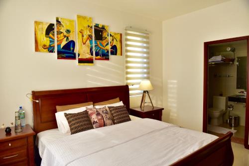 a bedroom with a bed and some paintings on the wall at SkyLounge Apartment Colombo in Colombo