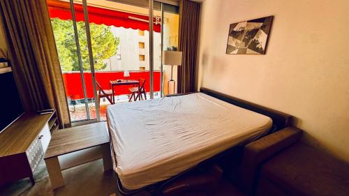 un petit lit dans une chambre avec une fenêtre dans l'établissement Studio climatisé 600m de la plage, à Cagnes-sur-Mer