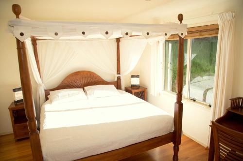 a bedroom with a canopy bed and a window at Avalon Resort in Kerikeri