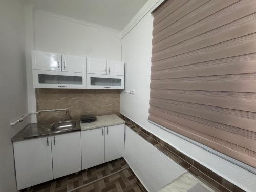 a kitchen with white cabinets and a wooden wall at Apartman Kaljević in Prijepolje