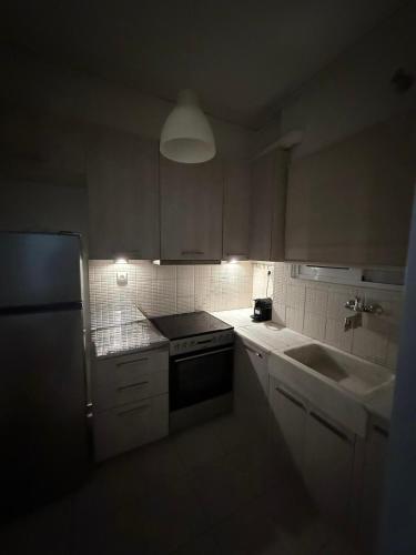 a kitchen with white cabinets and a sink and a refrigerator at Hidden Gem Apartment in Patra