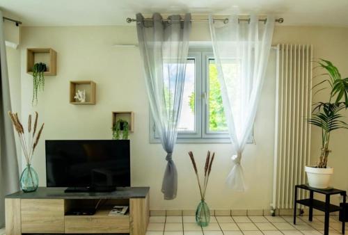 Elle comprend un salon doté de rideaux blancs et d'une télévision. dans l'établissement Charmant T2 Annecy, à Annecy