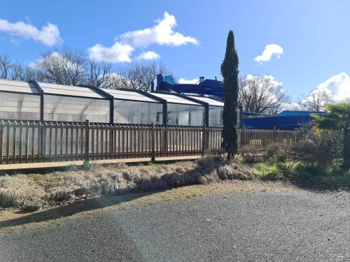 une clôture devant un bâtiment avec un arbre dans l'établissement Mobil Home climatisé, 2 ch, 5 pers, Wifi 30 mn du grand parc d'attraction Puy duFou, à La Boissière-de-Montaigu