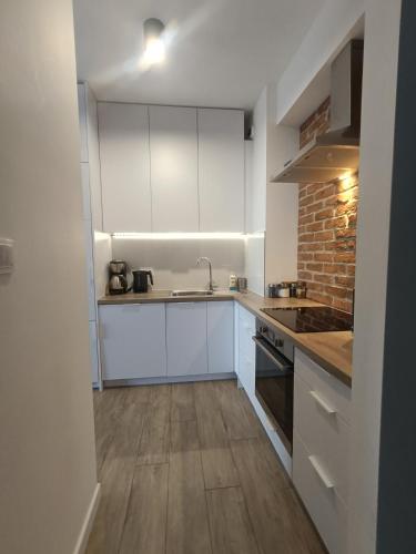 a kitchen with white cabinets and a brick wall at Apartament Siedlce in Siedlce