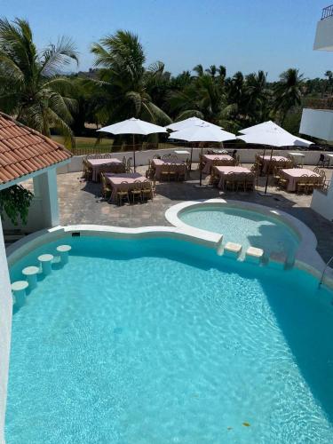a large blue swimming pool with tables and umbrellas at Hotel Costa Bugambilias in Manzanillo