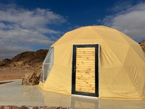 a yellow tent with a door in the desert at Nara Wadi RUM Camp in Wadi Rum