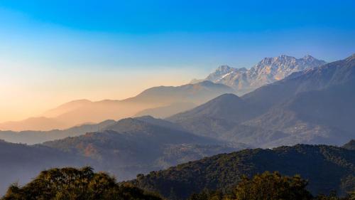 a view of a mountain range with the sun setting at Dormigo in Bīr