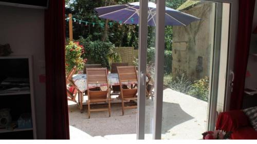 een patio met een tafel en een parasol bij Birchbank Cottage - Disney 30min in Coulommiers