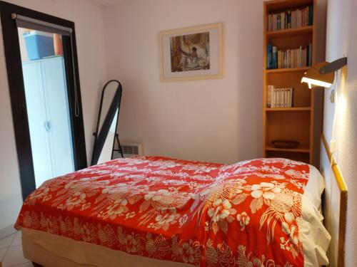 une chambre avec un lit avec une couverture rouge dans l'établissement CARIBOU T2 piscine - Axelle Loc'Appart, à Cannes