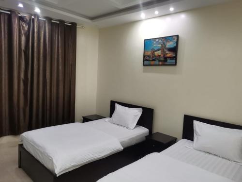 two beds in a room with white sheets at شقق مفروشه قارا in Qārā