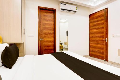 a bedroom with a white bed and wooden doors at Super Townhouse Eden Garden Zirakpur in Zirakpur