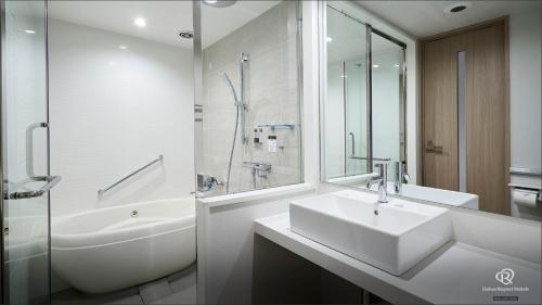 a white bathroom with a sink and a shower at Daiwa Roynet Hotel Kanazawa Eki Nishiguchi in Kanazawa