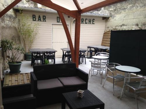 un patio con mesas, sillas y una mesa de bar. en Bar du Marché - Hôtel - Restaurant, en Langeais