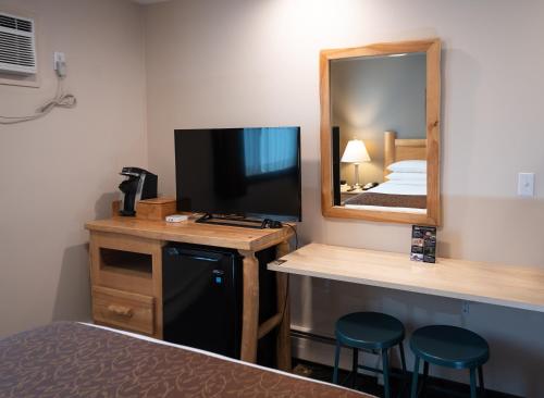 a hotel room with a tv and a bed and a mirror at Swiss Chalet Motel in Revelstoke