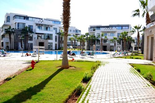 a palm tree in a park next to a pool at Hivernage Residence, Modern 2 Bedroom in Agadir