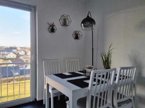 Un comedor con mesa y sillas y una ventana. en Wellnesshaus Dorfblick mit Outdoor-Jacuzzi und Infrarotkabine, NEU!, en Dreis-Brück