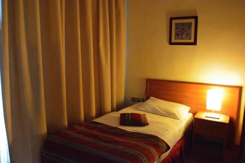 a bedroom with a bed and a lamp on a table at فندق أميري سويت in Umm Uthainah