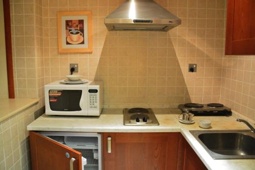 a small kitchen with a microwave and a sink at فندق أميري سويت in Umm Uthainah