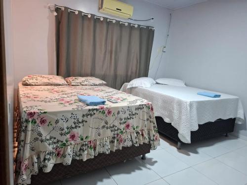 a room with two beds and a window at Estilo resort para confraternizar com hidro, piscina, garagem em casa tudo privativo, insira acima de 6 hóspedes para usar os 3 quartos in Sorriso