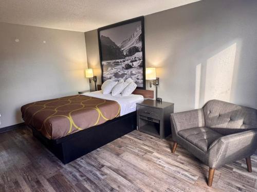 a hotel room with a bed and a chair at Super 8 by Wyndham Great Falls City Center in Great Falls