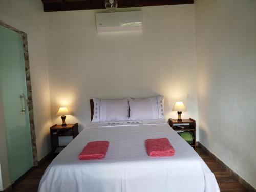 a bedroom with a white bed with two red towels on it at Chalés Vale dos Pássaros Refúgio nas montanhas in Paraty
