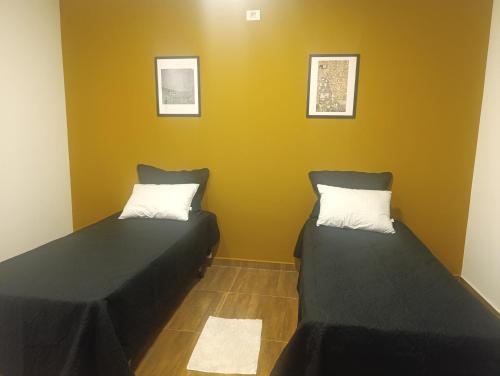 two beds in a room with yellow walls at Refúgio Atlântico in Mogi das Cruzes