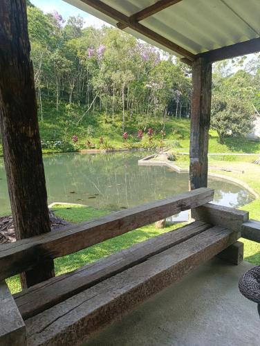 a wooden bench sitting in front of a pond at Refúgio Atlântico in Mogi das Cruzes